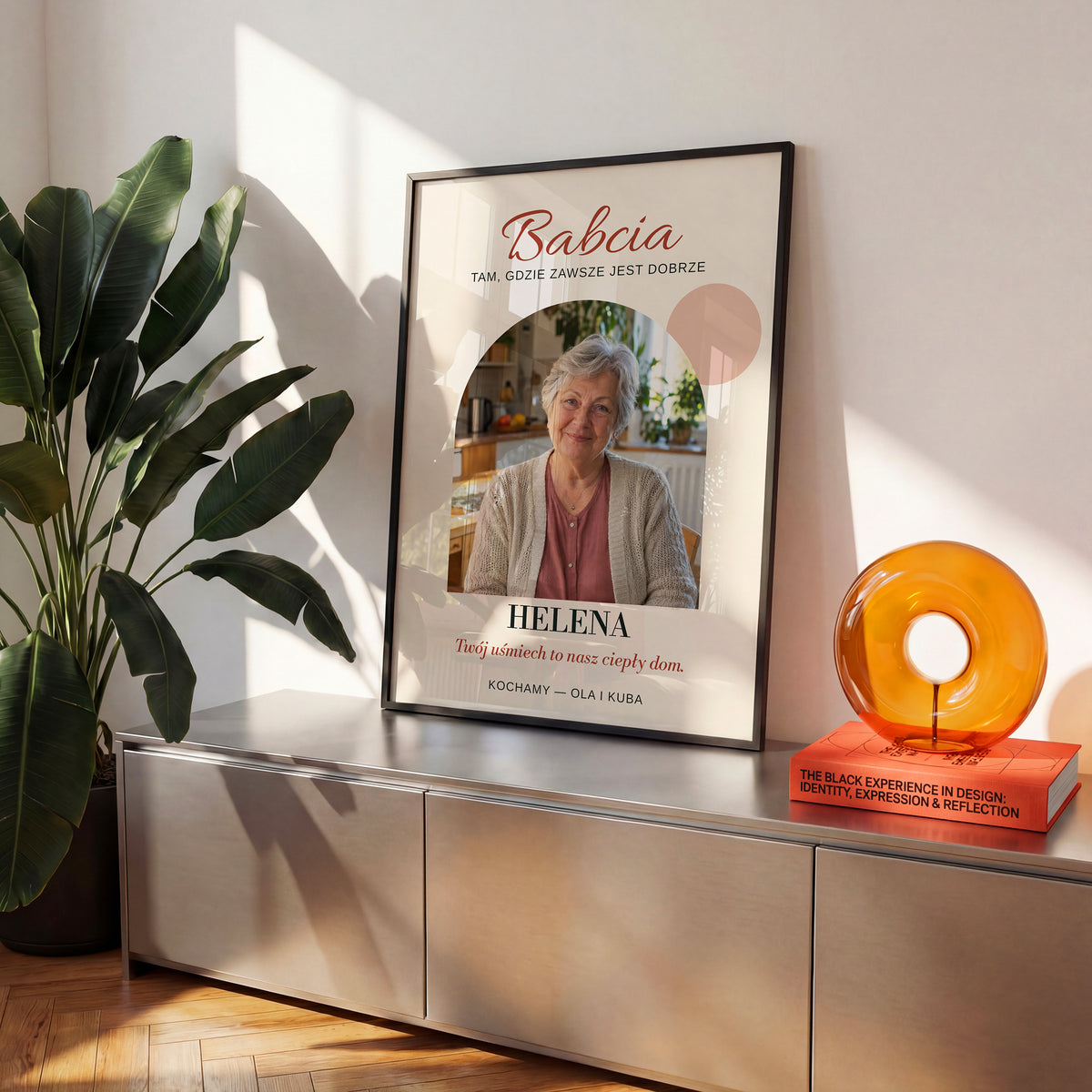 Personalizowany plakat BABCIA — CIEPŁY DOM w czarnej ramce na komodzie, z własnym zdjęciem i tekstem | C-PL-HEART-23-2130-NF