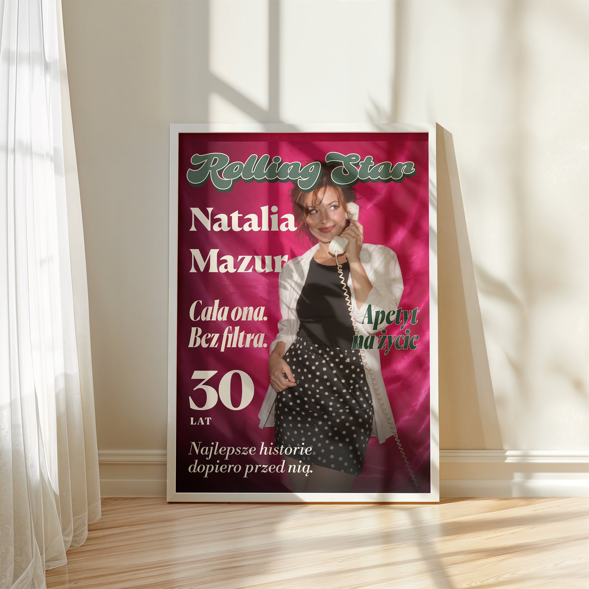 Personalizowany plakat Rolling Star w białej ramce przy oknie. Różowa satyna i litery retro tworzą osobistą okładkę ze zdjęciem.