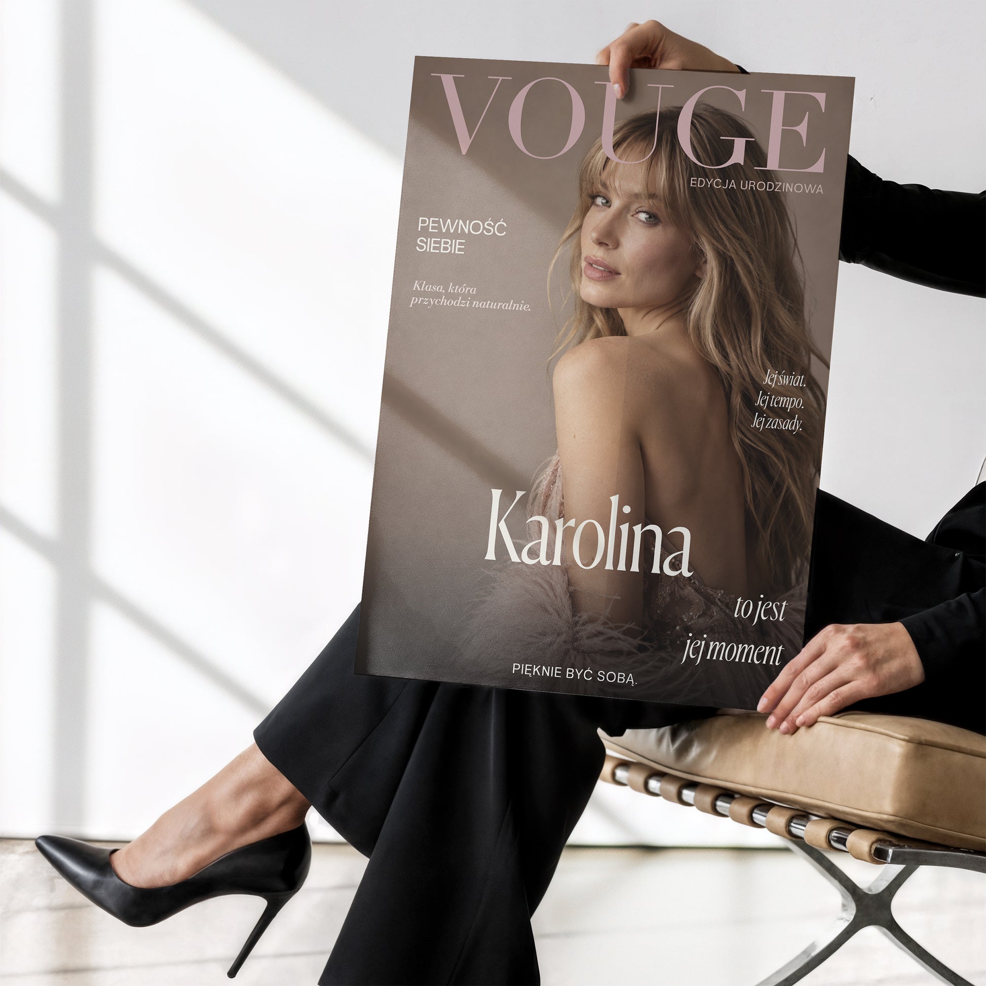 Personalizowany plakat Vouge Jej Moment bez ramki, trzymany w dłoniach. Pudrowe litery na ciepłym tle taupe tworzą osobistą okładkę ze zdjęciem.