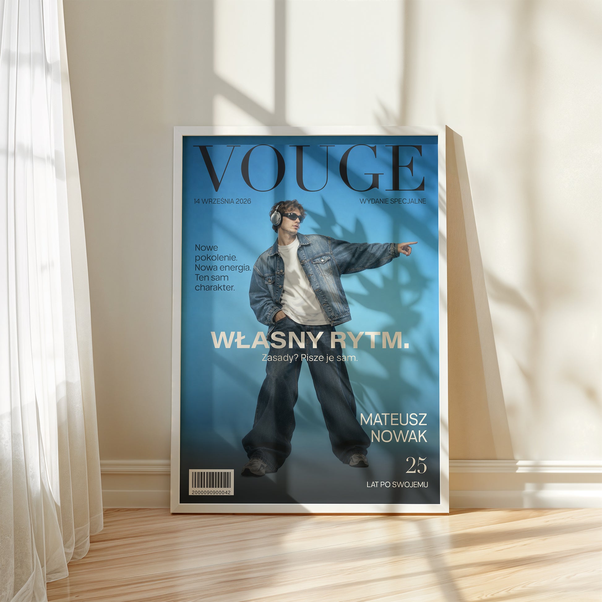 Personalizowany plakat Vouge Własny Rytm w białej ramce przy oknie. Niebieskie tło i szerokie jasne hasło tworzą osobistą okładkę ze zdjęciem.