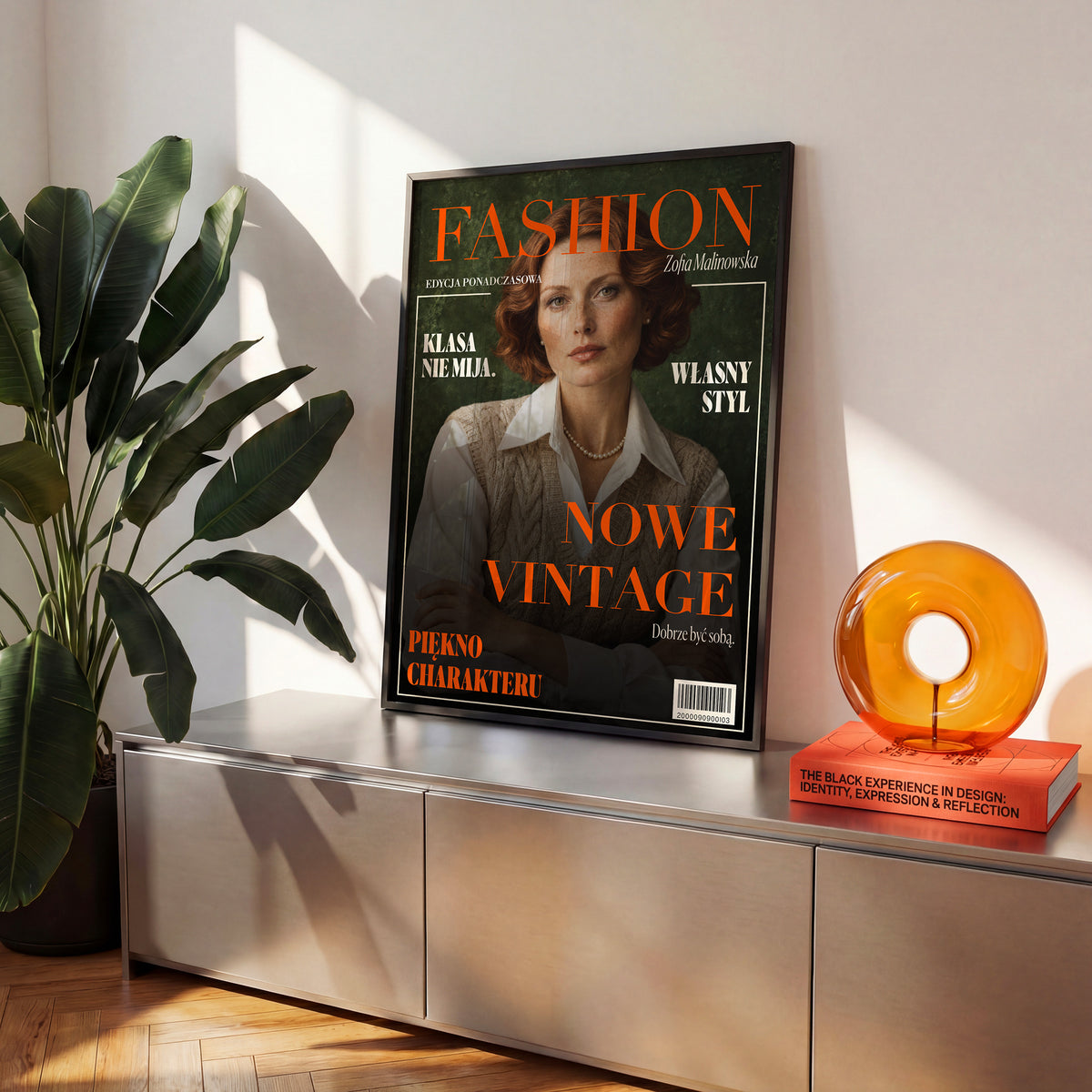 Personalizowany plakat Fashion Nowe Vintage w czarnej ramce na komodzie. Zieleń, pomarańcz i szeryfowe napisy tworzą osobistą okładkę ze zdjęciem.