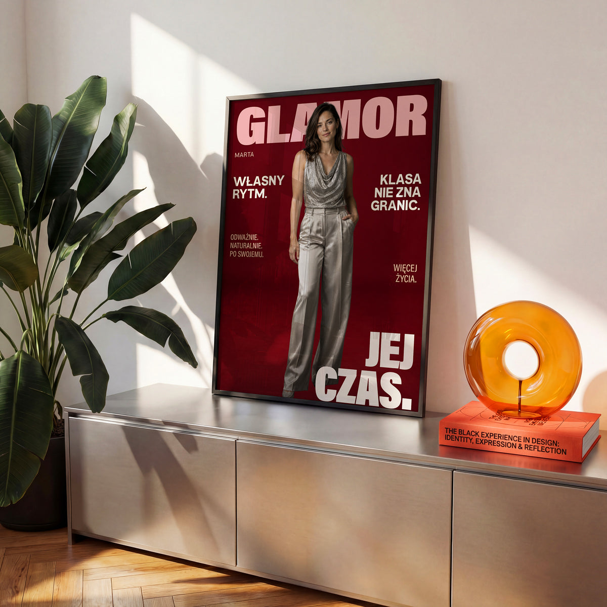 Personalizowany plakat GLAMOR w czarnej ramce na komodzie. Bordowe tło, portret i jasne napisy na modowej okładce portretowej.