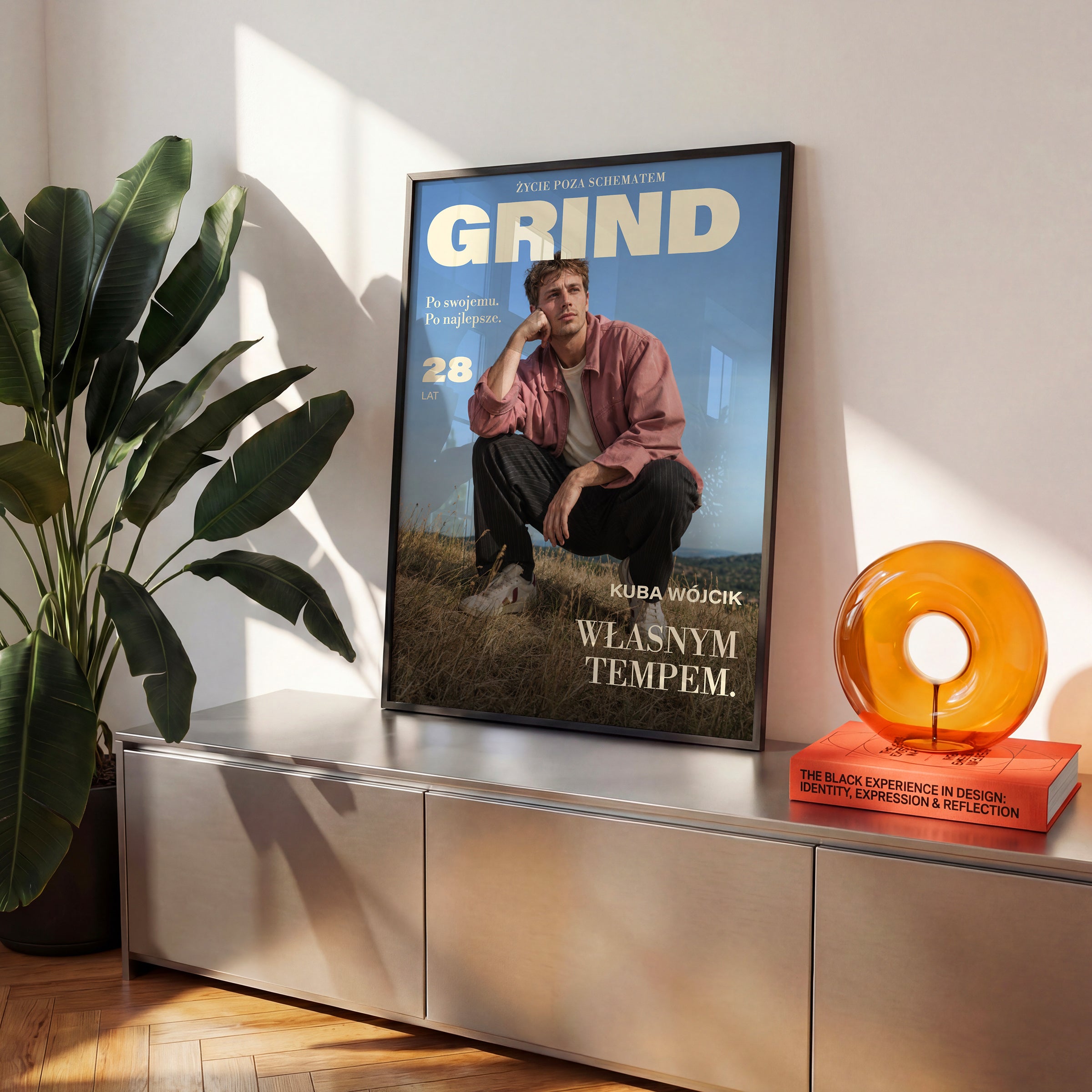 Personalizowany plakat GRIND — WŁASNYM TEMPEM w czarnej ramce ustawiony na komodzie, z własnym portretem, imieniem i napisami na okładce magazynu.