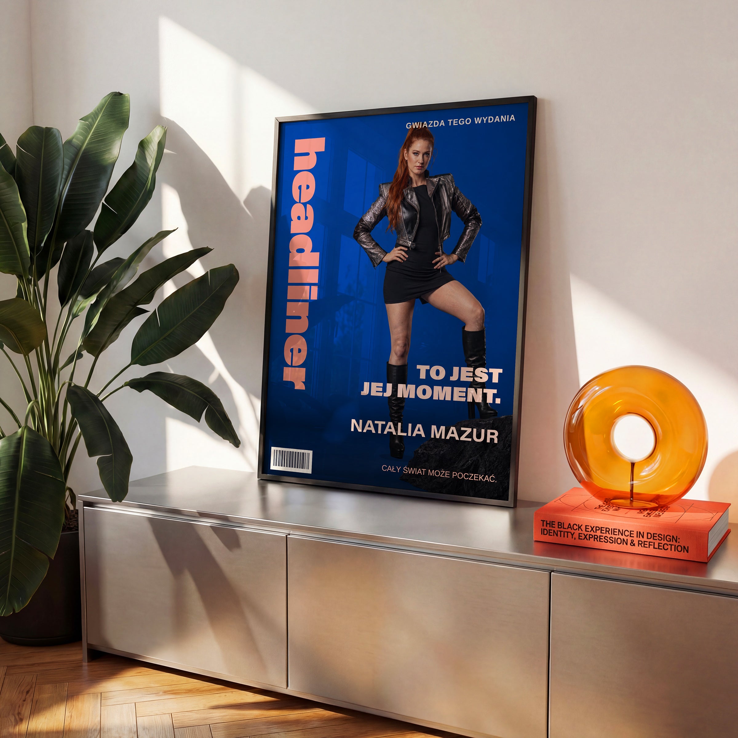Personalizowany plakat HEADLINER — JEJ MOMENT w czarnej ramce ustawiony na komodzie, z własnym portretem, imieniem i napisami na okładce magazynu.