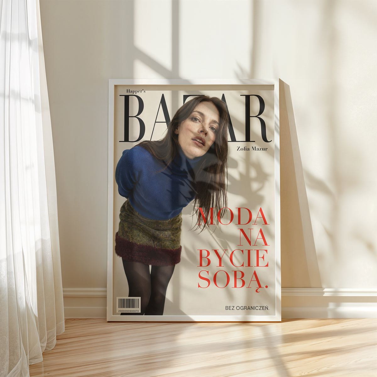 Personalizowany plakat Happer’s BAZAR w białej ramce przy oknie. Kremowe tło, portret i czerwone hasło na modowej okładce portretowej.