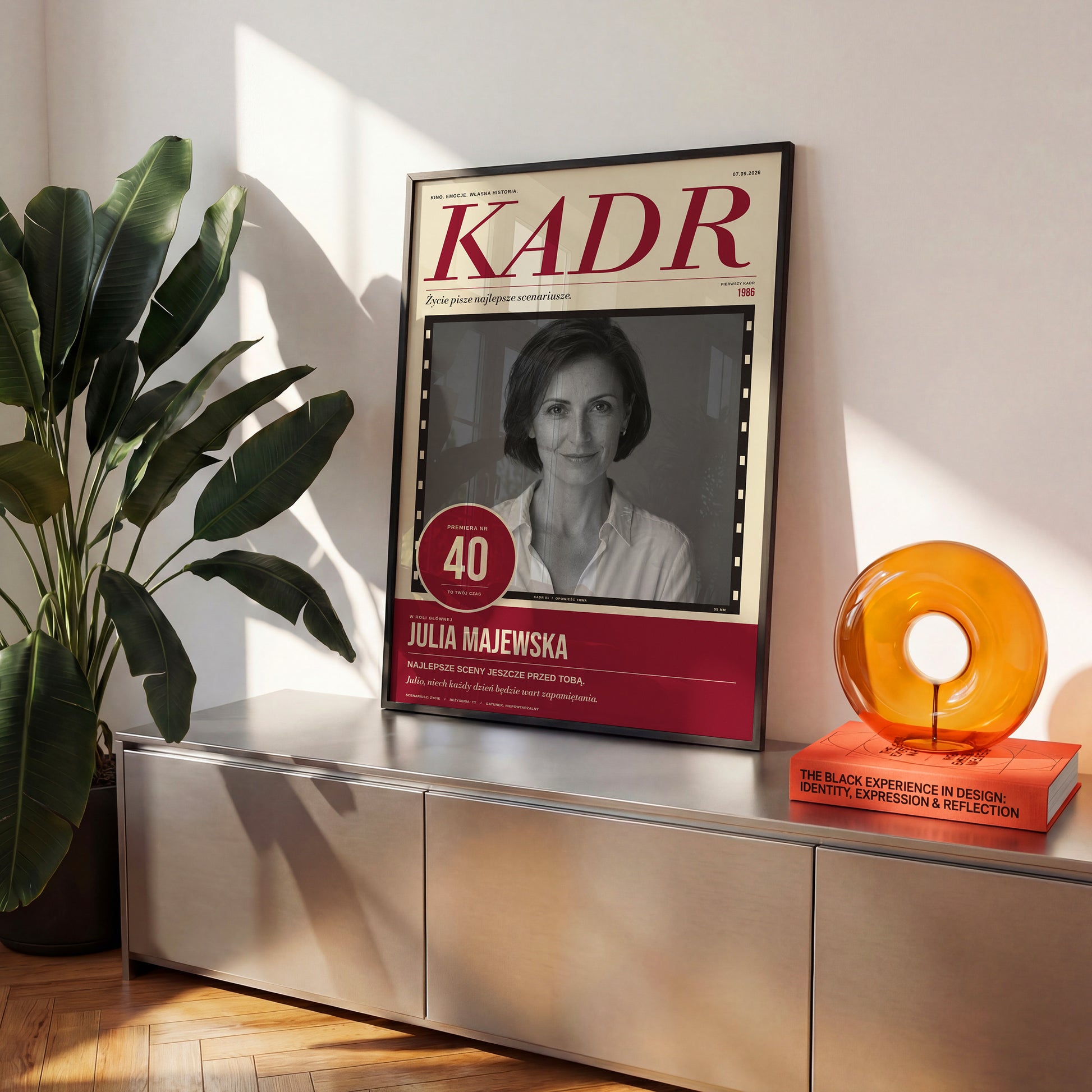 Plakat KADR w czarnej ramce na komodzie, portret w klatce filmowej i imię głównej gwiazdy | C-PL-COVMAG-10-2130-NF