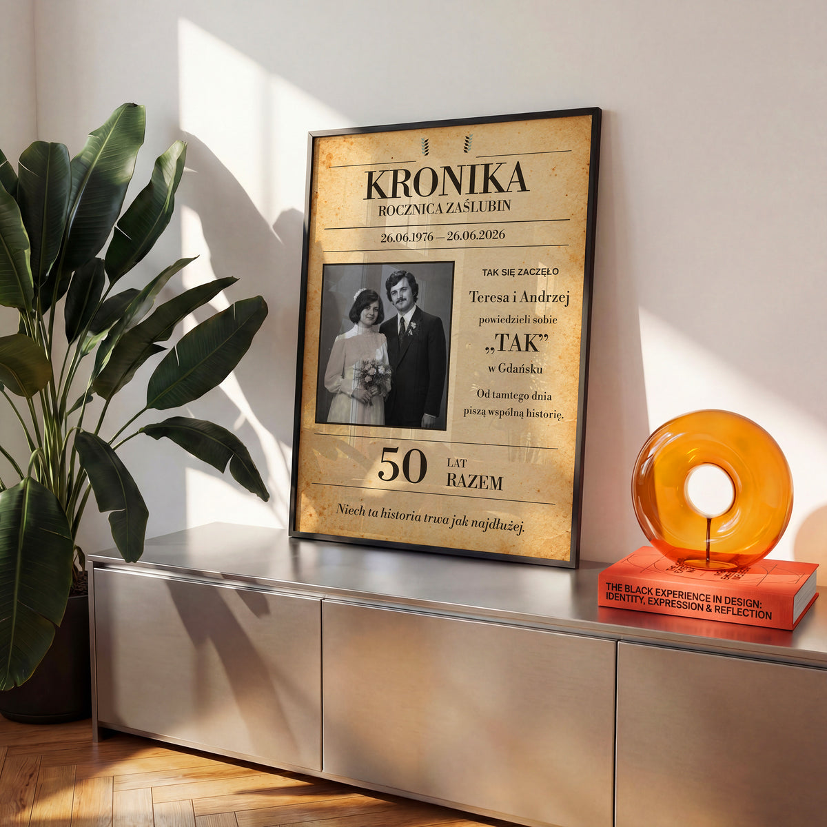 Personalizowany plakat KRONIKA ZAŚLUBIN w czarnej ramce na komodzie, z własnym zdjęciem i tekstem | C-PL-HEART-13-2130-NF