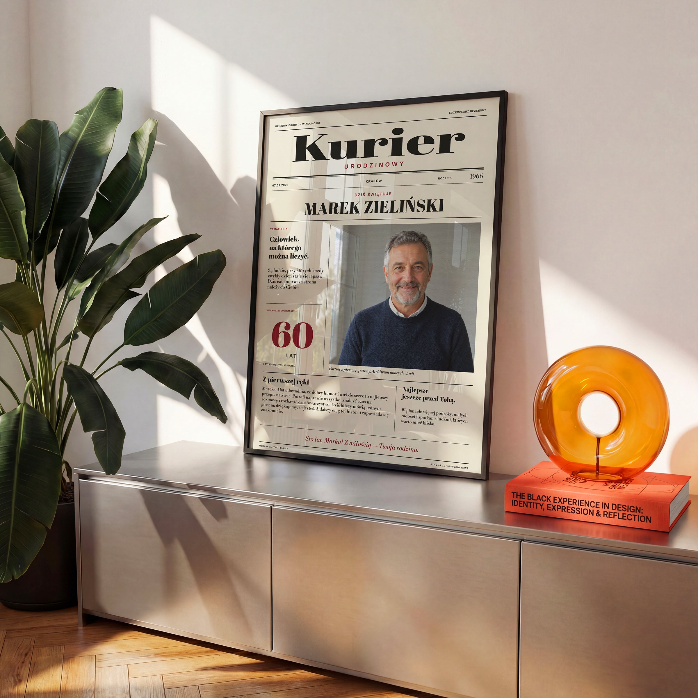 Personalizowana gazeta KURIER w czarnej ramce na komodzie, nagłówek z imieniem i własny artykuł urodzinowy | C-PL-GAZ-6-2130-NF