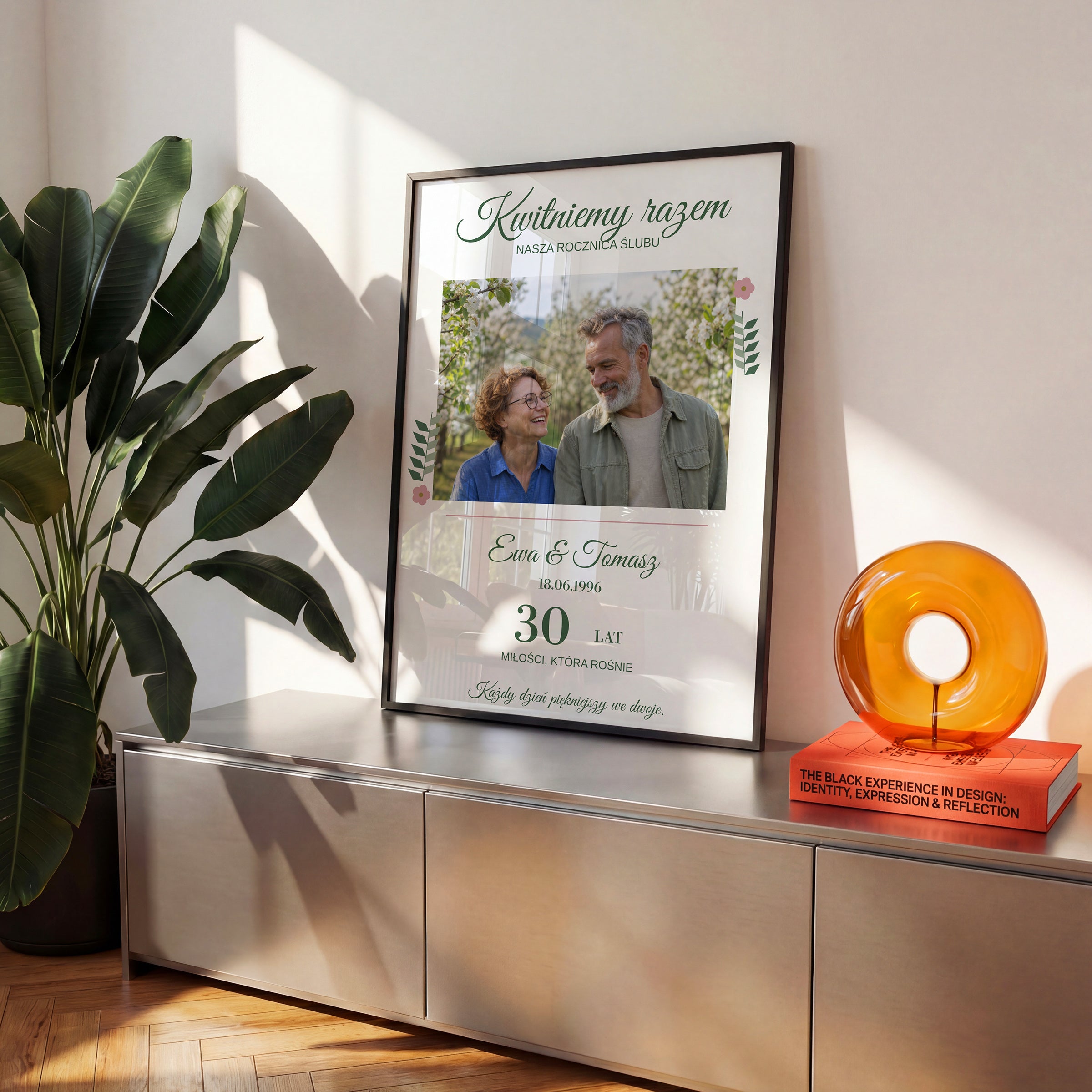 Personalizowany plakat KWITNIEMY RAZEM w czarnej ramce na komodzie, z własnym zdjęciem i tekstem | C-PL-HEART-12-2130-NF
