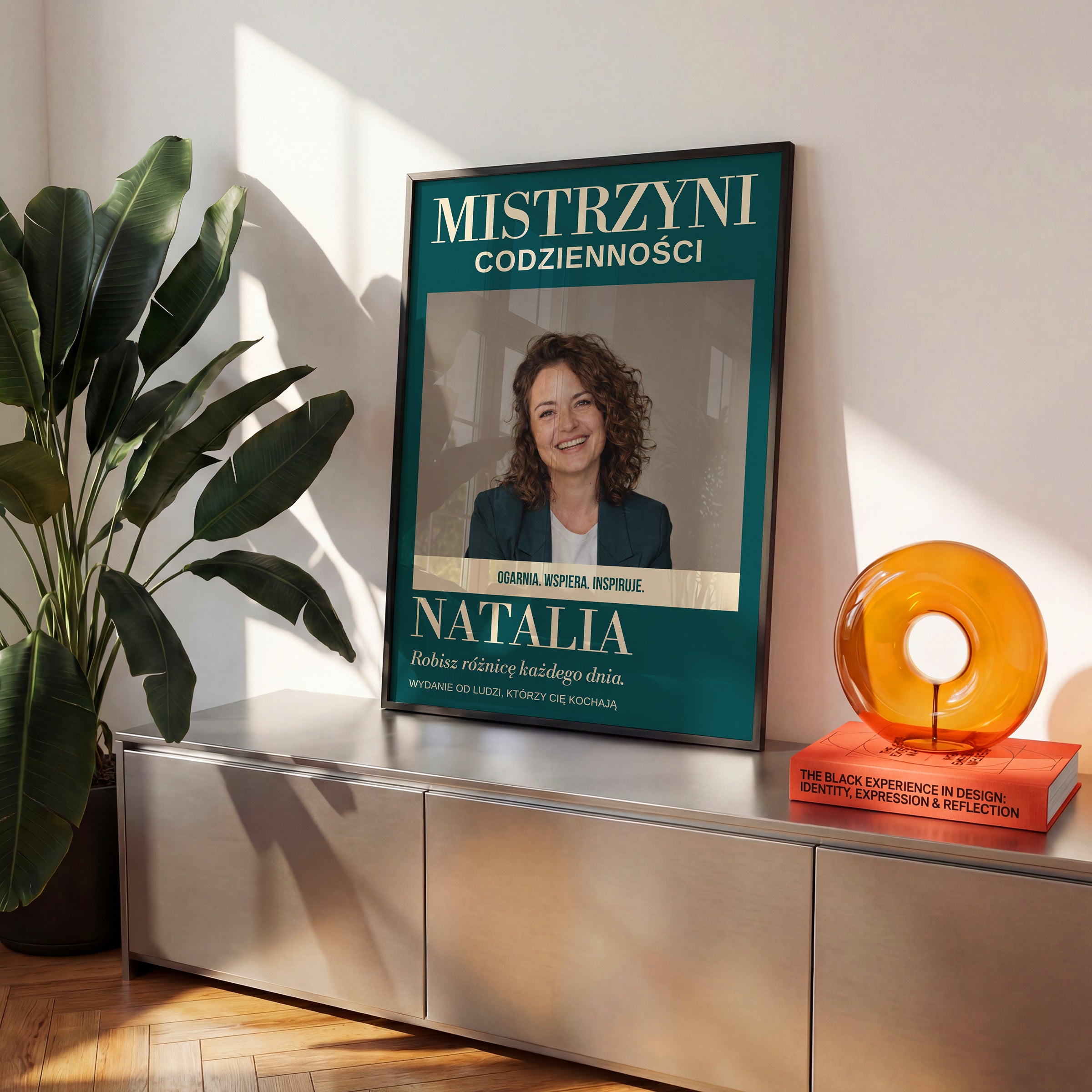 Personalizowany plakat MISTRZYNI CODZIENNOŚCI w czarnej ramce na komodzie, z własnym zdjęciem i tekstem | C-PL-COVMAG-20-2130-NF