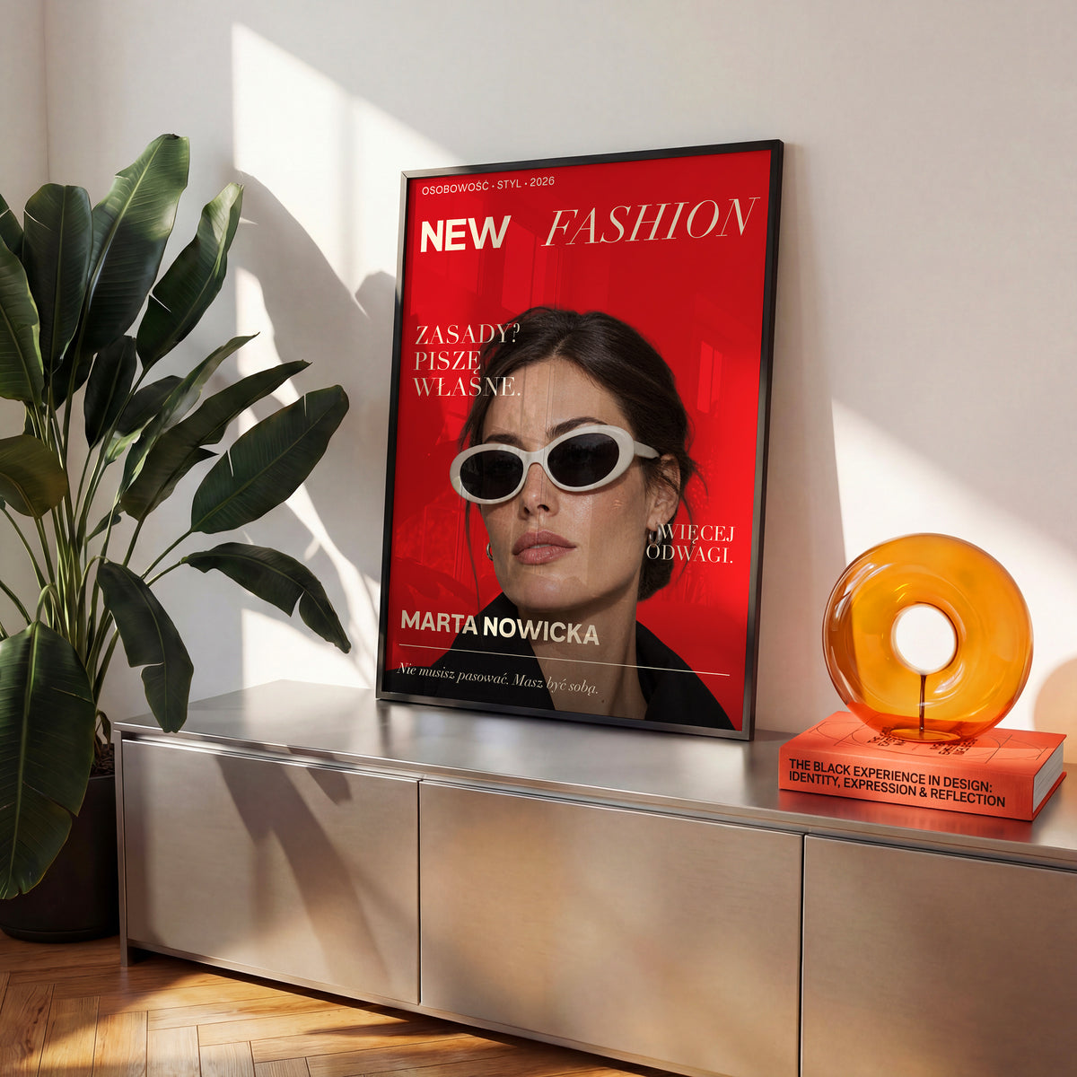 Personalizowany plakat New Fashion w czarnej ramce na komodzie. Portret na czerwonym tle z białą typografią. Dekoracja ze zdjęciem.