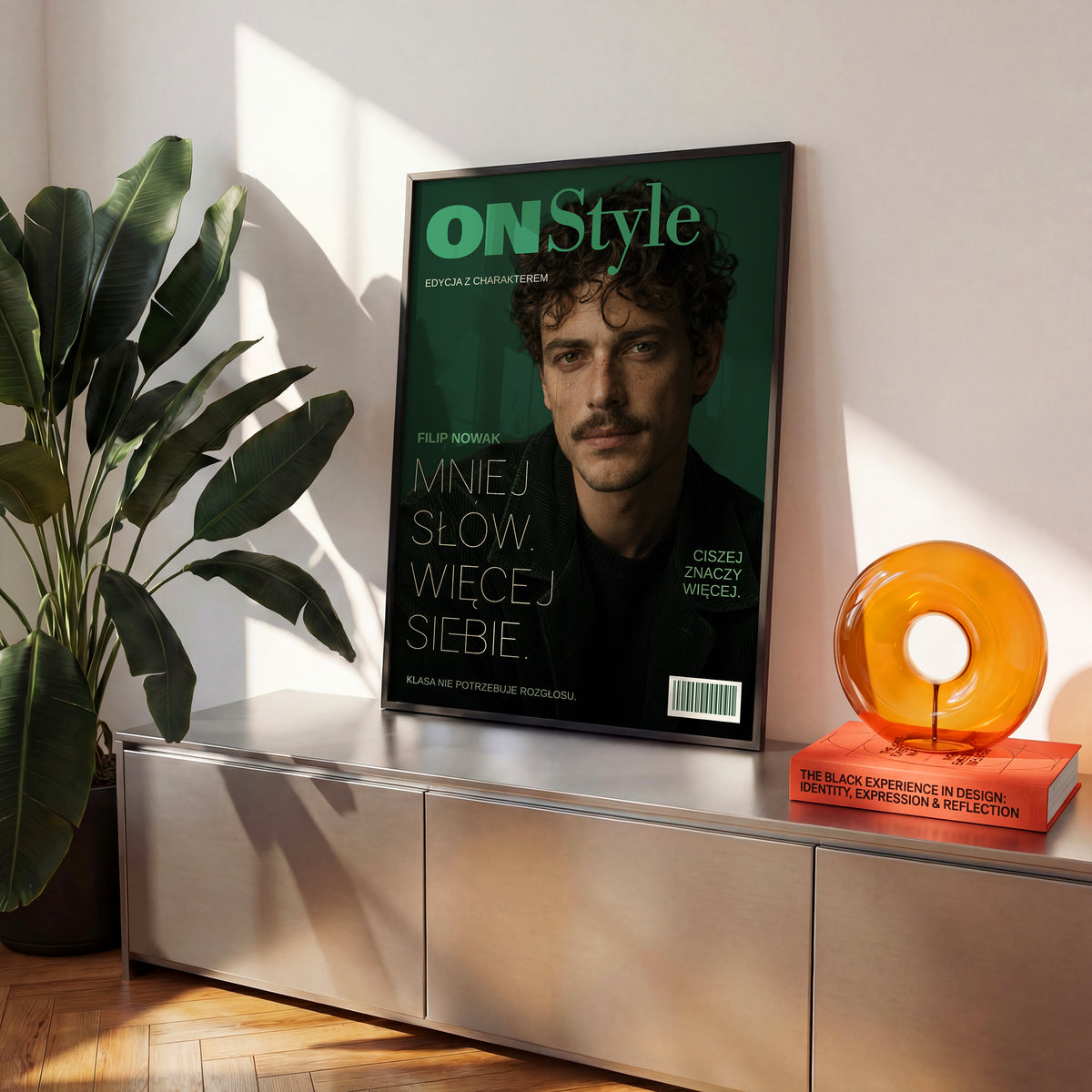 Personalizowany plakat ON STYLE — CISZEJ ZNACZY WIĘCEJ w czarnej ramce ustawiony na komodzie, z własnym portretem, imieniem i napisami na okładce magazynu.