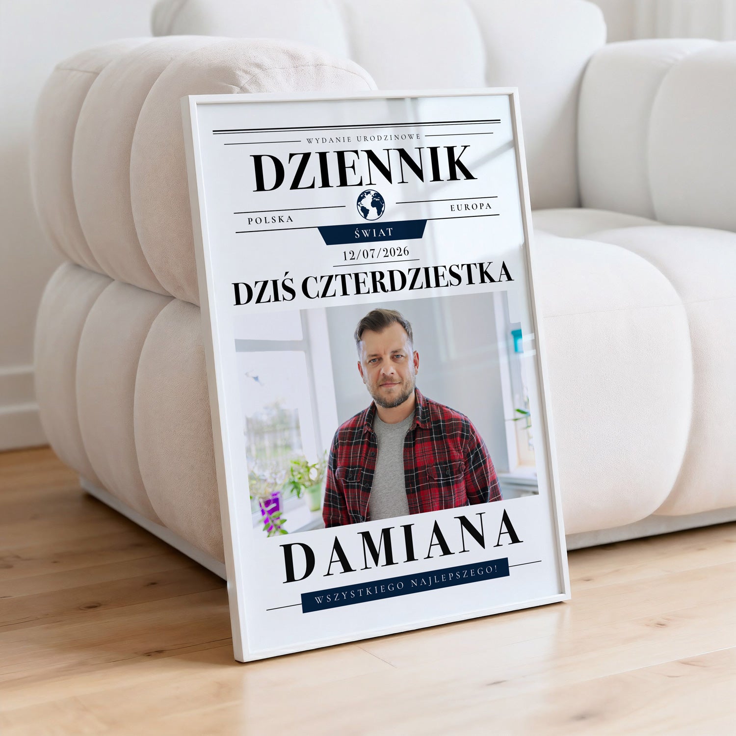 Personalizowany plakat na urodziny dziennik w białej ramce oparty o jasną pikowaną kanapę