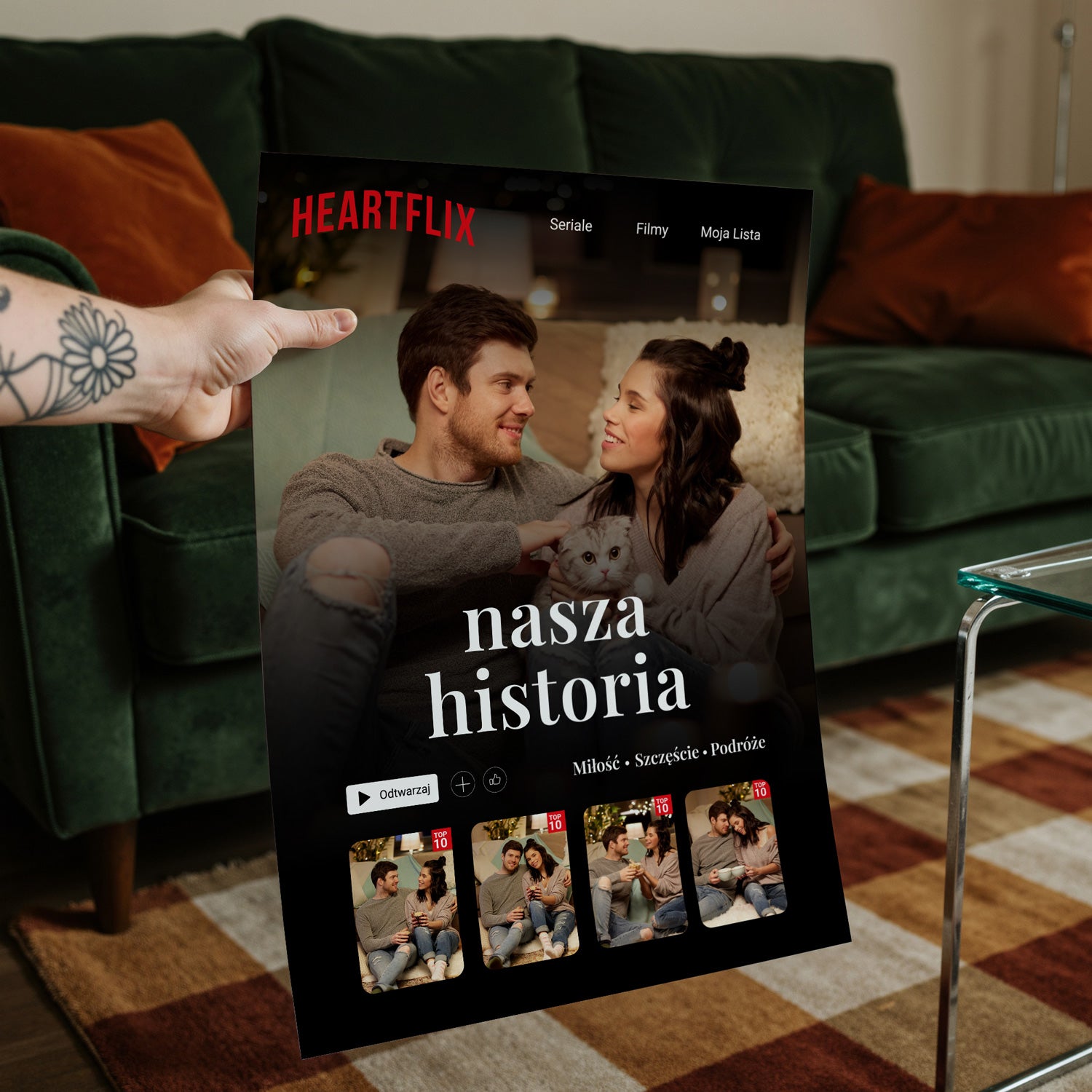 Plakat Heartflix trzymany w salonie z zieloną sofą w tle - czarna ramka