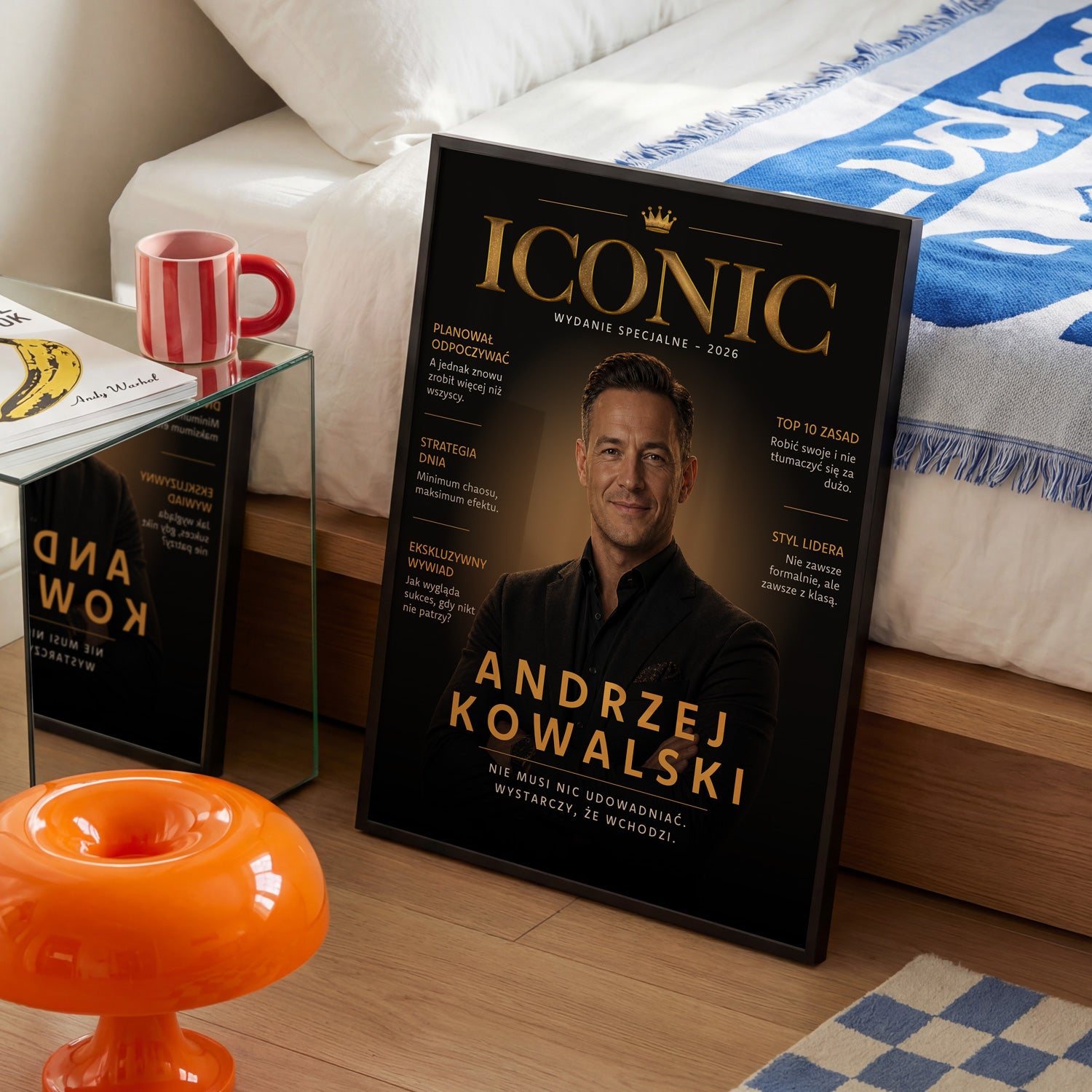 Plakat Iconic okładka magazynu w czarnej ramce ustawiony w sypialni obok łóżka i czerwonego kubka