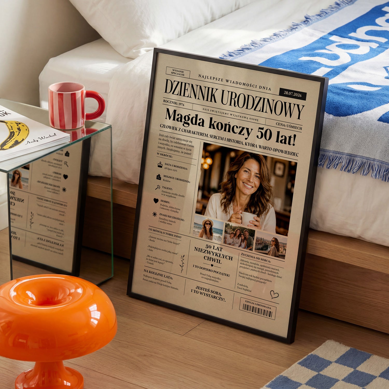 Personalizowany plakat urodzinowy w stylu dziennika gazetowego w czarnej ramce, ustawiony w sypialni obok łóżka i czerwonego kubka
