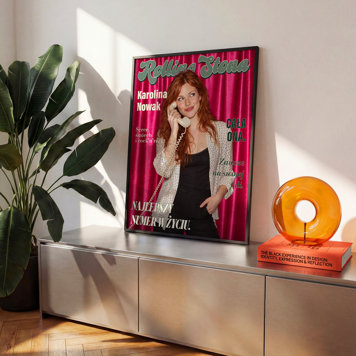 Personalizowany plakat Rolling Stona w czarnej ramce na komodzie. Różowa satyna, portret i tytuł retro na modowej okładce portretowej.