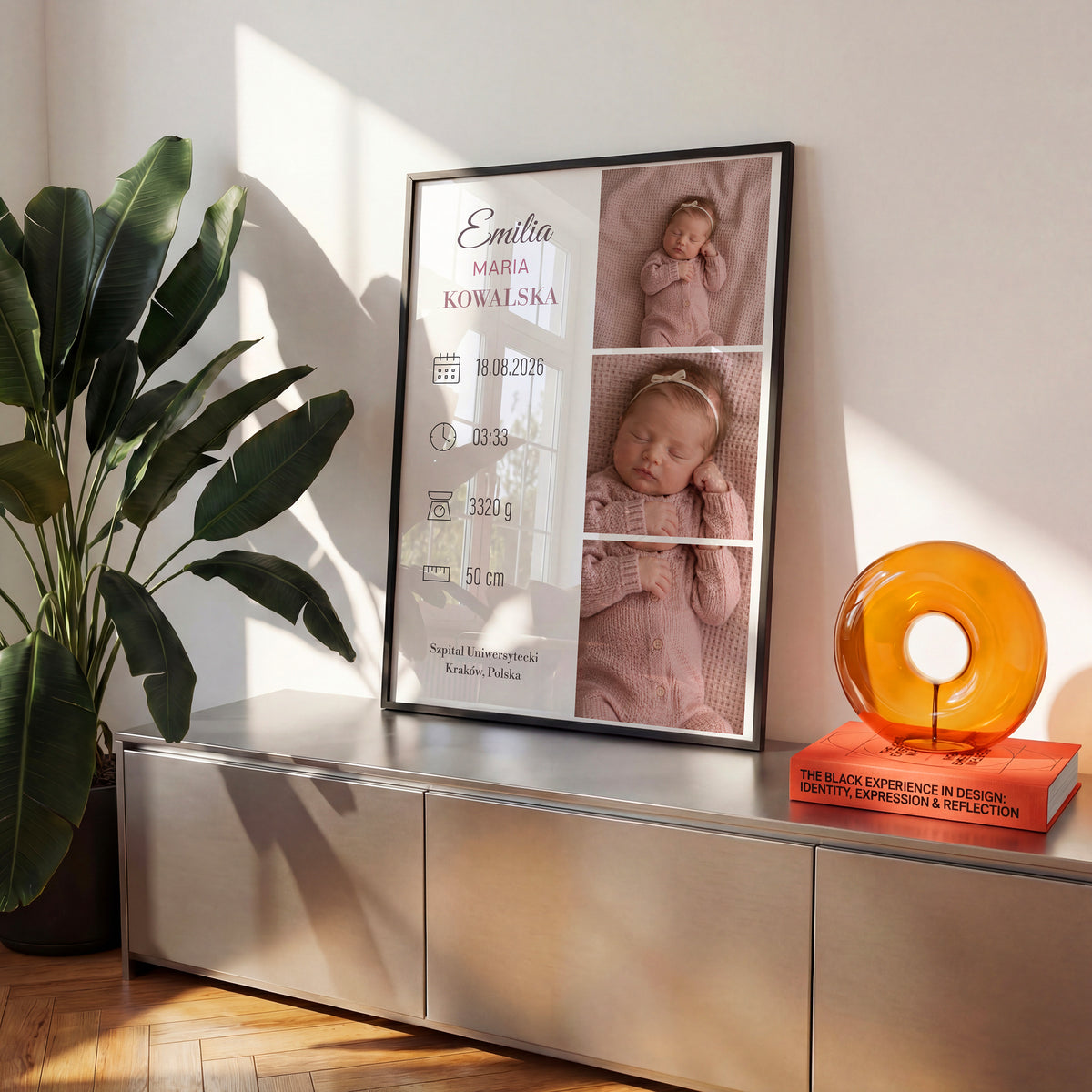 Personalizowany plakat Różowy Album w czarnej ramce na komodzie. Różowy album zdjęć dziecka z imieniem i danymi narodzin.