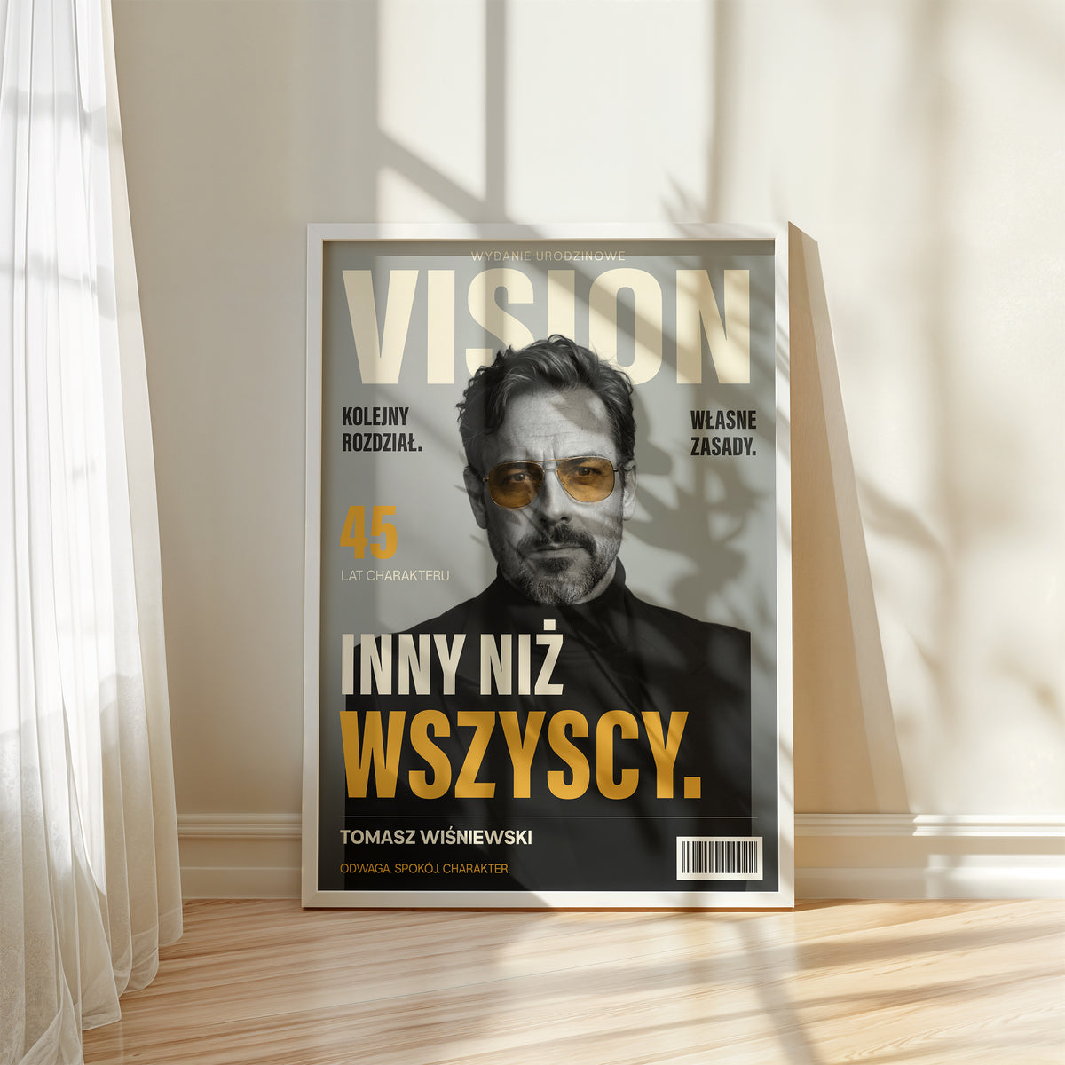 Personalizowany plakat VISION — WŁASNE ZASADY w białej ramce przy oknie, z własnym portretem, imieniem i napisami na okładce magazynu.