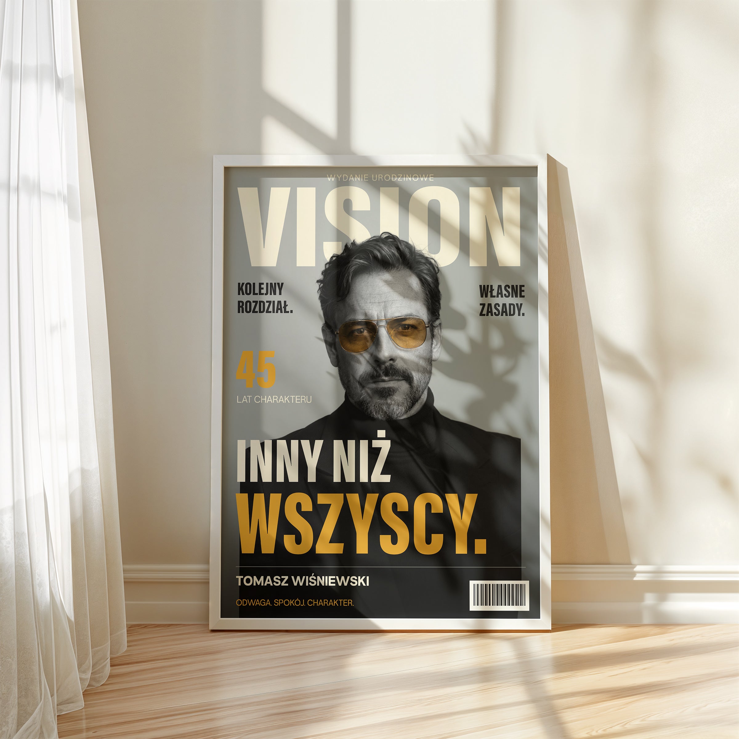 Personalizowany plakat VISION — WŁASNE ZASADY w białej ramce przy oknie, z własnym portretem, imieniem i napisami na okładce magazynu.