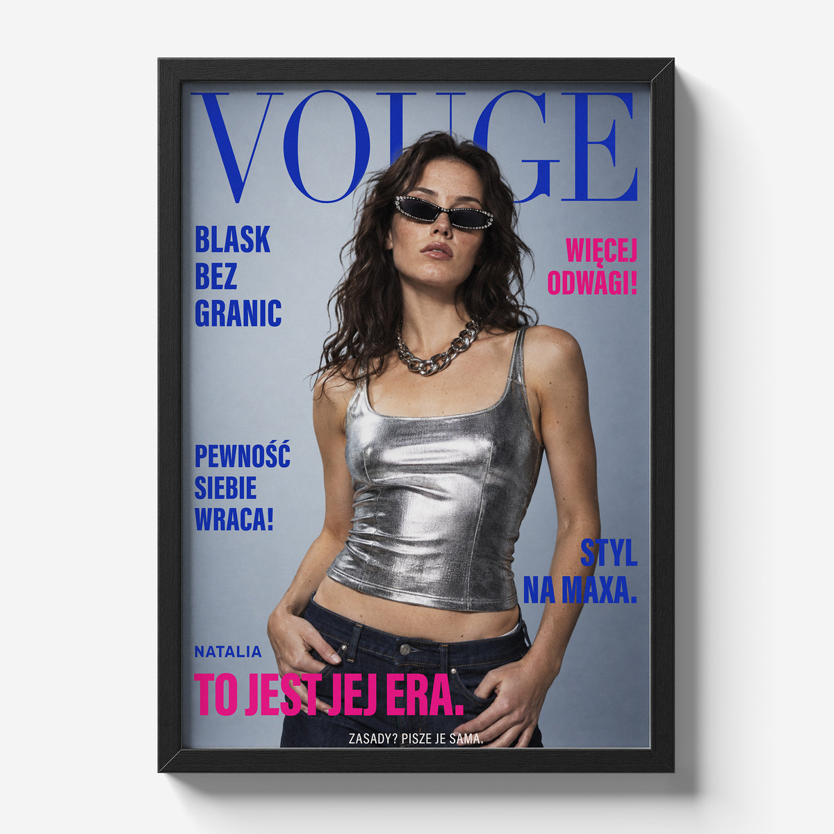 Personalizowany plakat Vouge Jej Era w czarnej ramce na jasnym tle. Kobaltowy tytuł, różowe hasła i portret na modowej okładce portretowej.