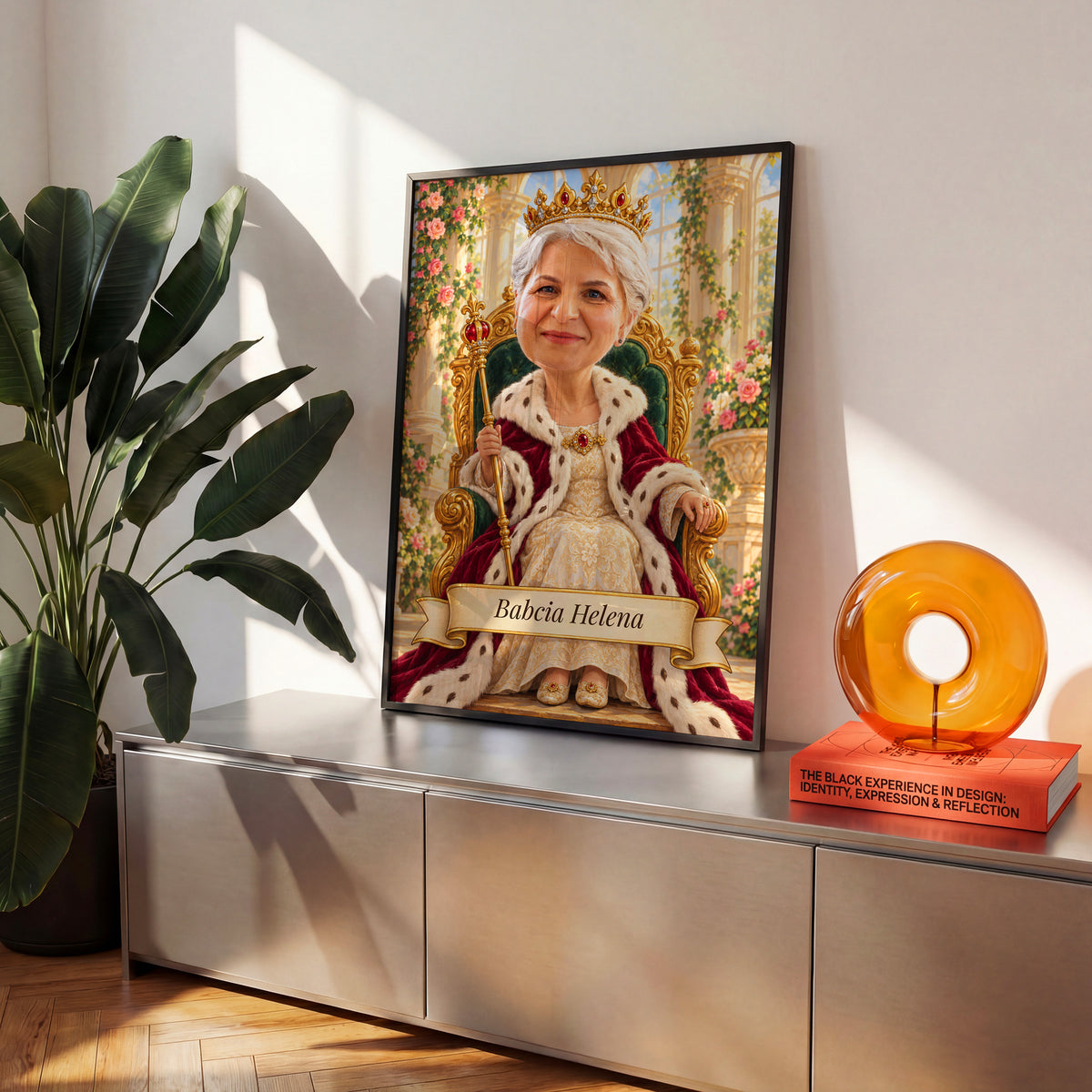 Królowa Babcia — plakat w czarnej ramie na komodzie we wnętrzu, z karykaturą babci w koronie na złotym tronie, w jasnej sali z kwiatami. C-PL-KAR-07-2130-NF