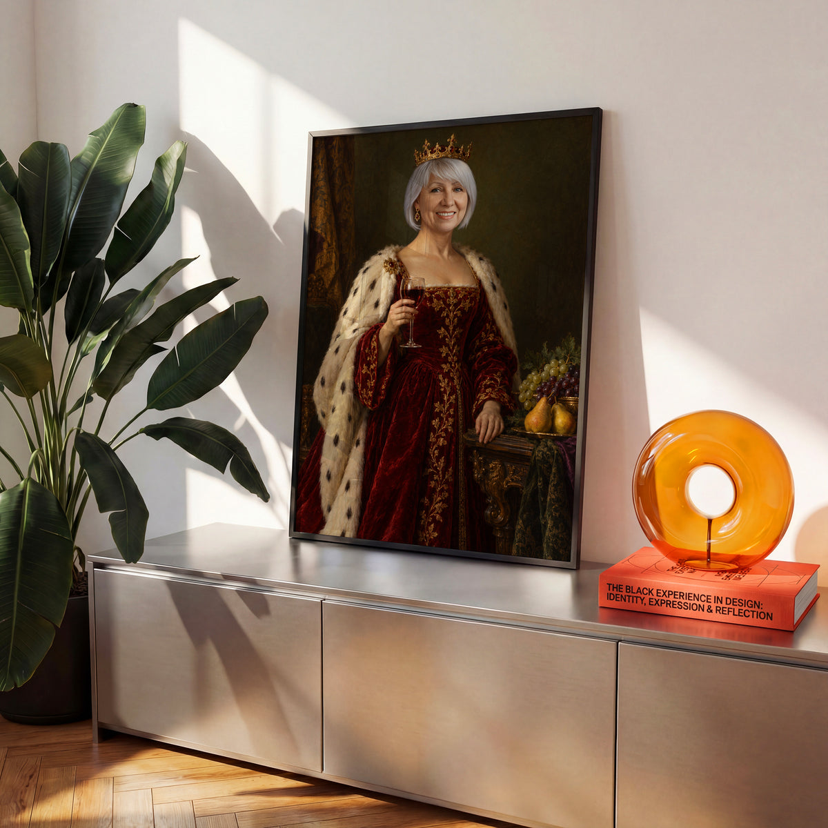 Królowa Wina — plakat w czarnej ramie na komodzie we wnętrzu, z portretem kobiety w bordowej sukni i koronie, z kieliszkiem czerwonego wina. C-PL-ROY-11-2130-NF