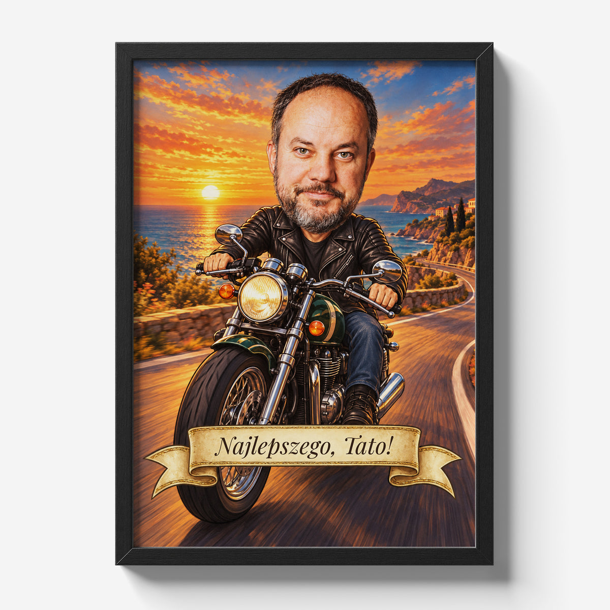 Motocyklista — plakat ze zdjęcia w czarnej ramie na jasnym tle, z karykaturą mężczyzny na motocyklu, na nadmorskiej drodze o zachodzie słońca.