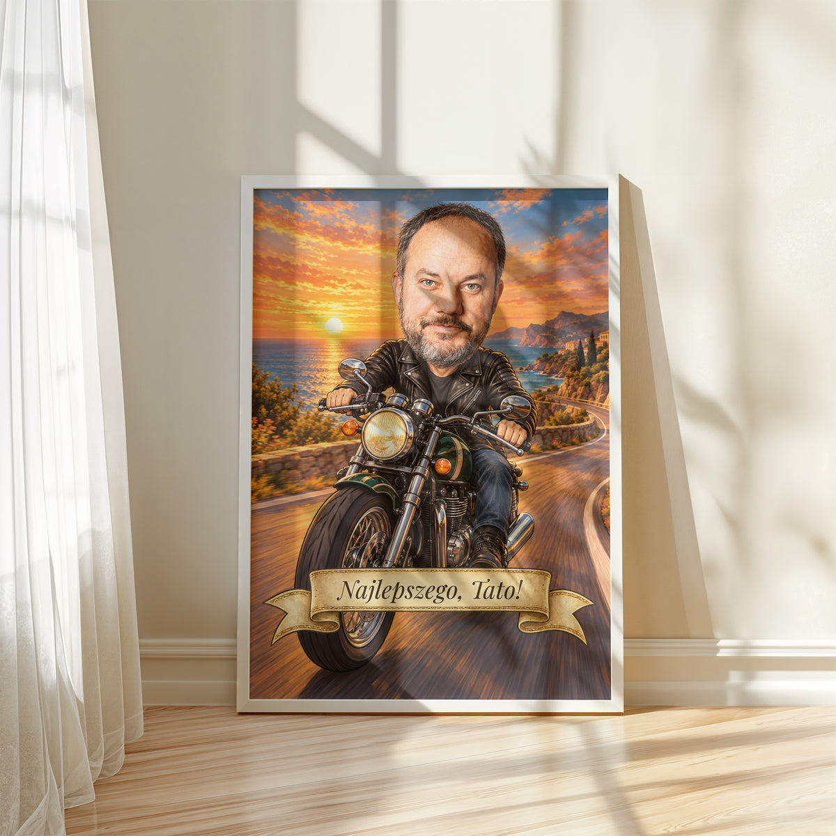 Motocyklista — plakat w białej ramie przy oknie, z karykaturą mężczyzny na motocyklu, na nadmorskiej drodze o zachodzie słońca. C-PL-KAR-06-2130-NF