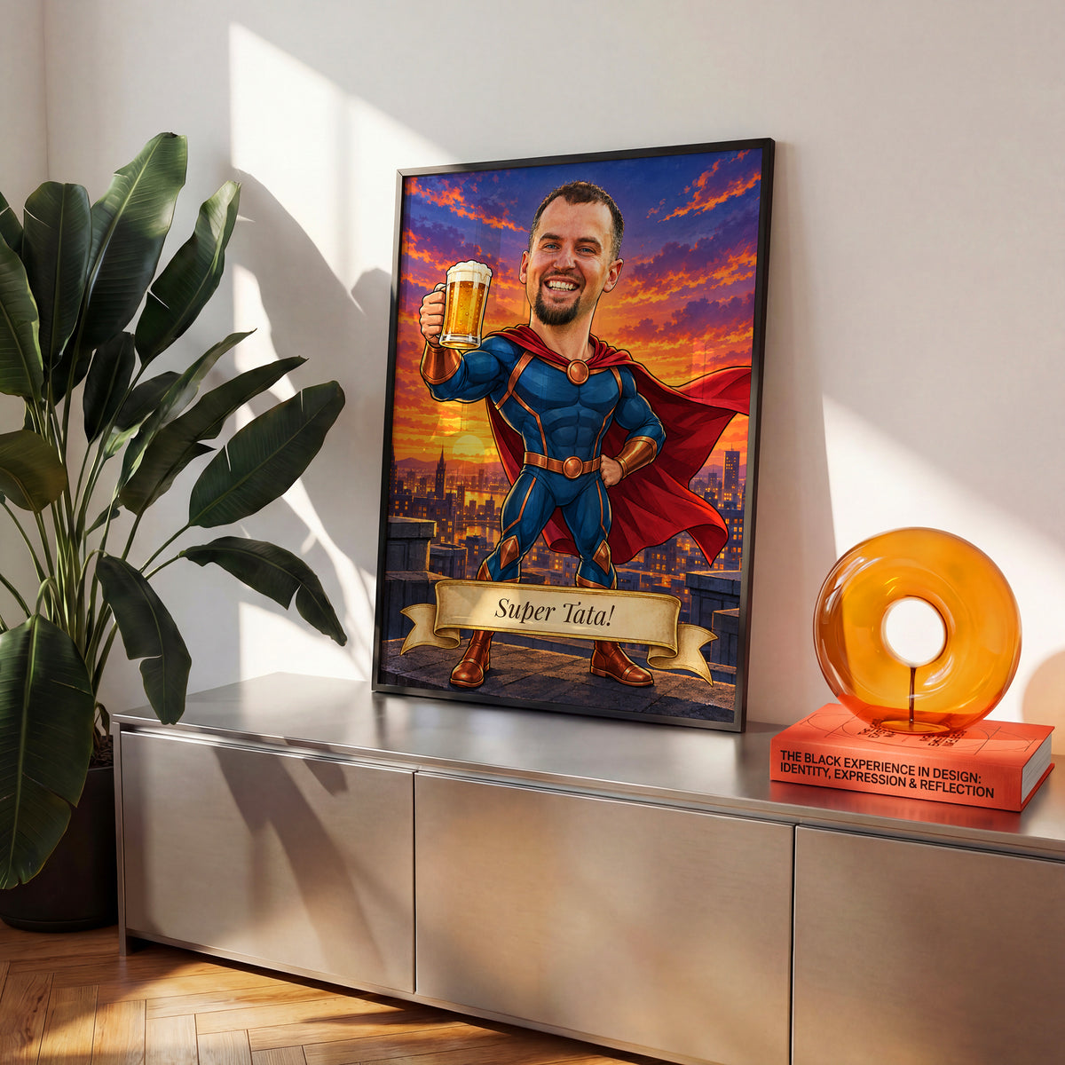 Super Tata — plakat w czarnej ramie na komodzie we wnętrzu, z karykaturą taty jako superbohatera w pelerynie, z kuflem piwa na tle miasta. C-PL-KAR-08-2130-NF